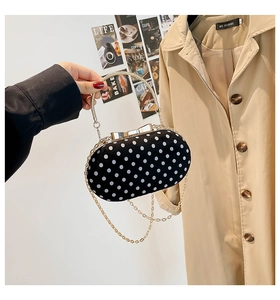 Close-up of velvet polka dot bag with gold bow clasp and round metal handle detail
