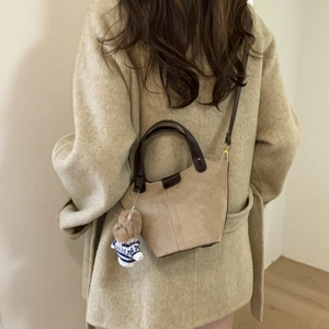 Detail of khaki suede crossbody bag with leather trim and cute bear keychain charm