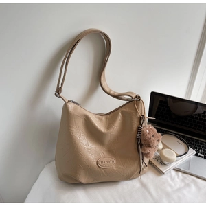 Detail of retro pleated leather tote bag in beige with a cute plush bear charm