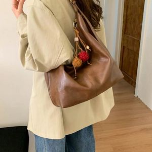 Brown large faux leather tote bag with colorful pompom charm worn on the shoulder