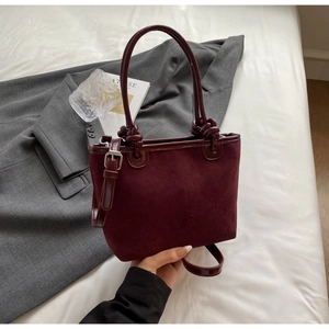 Detail of burgundy suede bucket bag with embossed logo and premium leather handles