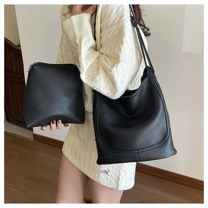 Detail of black pebbled leather bucket bag set with matching zip pouch shown on model