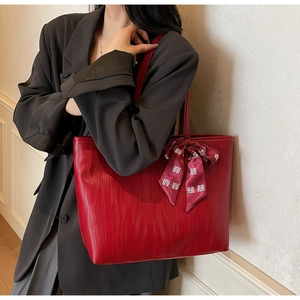 Detalle de bolso tote rojo con textura de cuero ondulado y lazo decorativo rojo