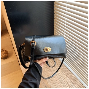 Détail d'un sac à main noir brillant en similicuir avec fermoir doré et bandoulière réglable