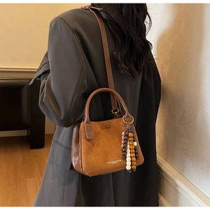 Detailansicht der braunen Retro-Beuteltasche mit Holzperlen und Logo-Prägung