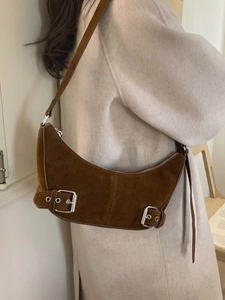 Brown suede crescent shoulder bag with silver buckles shown on a female model