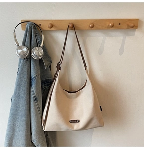 Detailed macro view of high-quality canvas tote bag with premium metal brand logo plaque