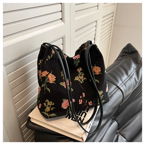 Detail of floral embroidery on a black canvas bucket bag with elegant thin shoulder straps