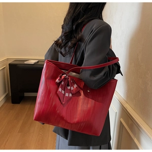 Detail view of red tote bag with wave texture and festive bow scarf accessory