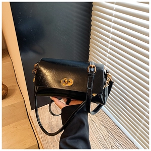 Vue détaillée d'un sac bandoulière en cuir noir brillant avec un fermoir doré ovale
