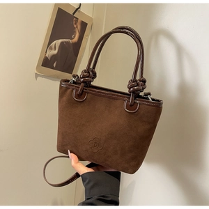 Detail of vintage brown suede bucket bag with knotted handle and embossed logo