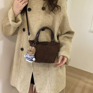 Detail of dark brown faux suede crossbody bucket bag with cute plush puppy charm