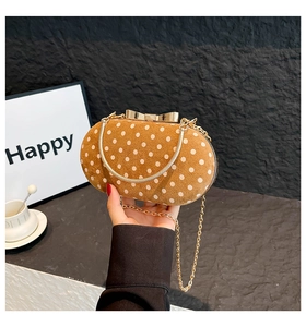 Detailed shot of brown suede clutch with white dots and gold bow buckle finish