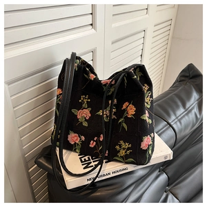 Close-up of floral embroidery on a black canvas bucket bag with elegant shoulder straps