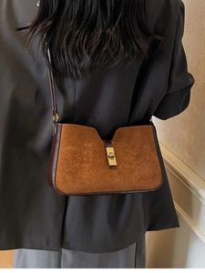 Sac seau vintage en daim marron avec fermoir doré porté à l'épaule par un mannequin
