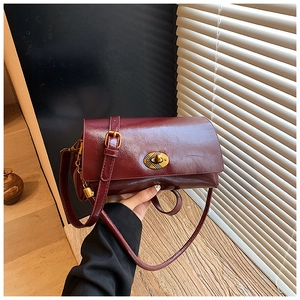 Détail du sac bandoulière vintage bordeaux avec fermoir rotatif ovale doré poli