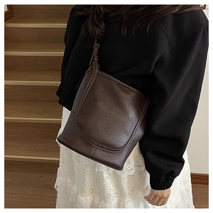Close-up of deep brown litchi pattern leather shoulder bag on model with vintage style