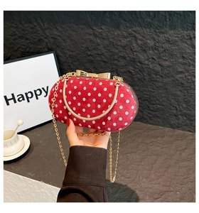 Close-up of red polka dot handbag featuring golden bow clasp and round metal handle