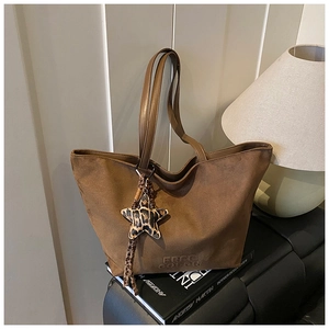 Detail of dark brown suede tote bag with leopard star charm and embossed branding