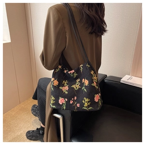 Detailed embroidery on a black canvas bucket bag featuring colorful floral patterns