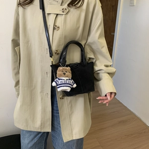 Detailed shot of black crossbody bag with matte texture and cute plush bear keychain charm