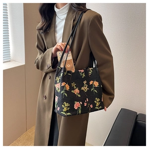 Detail of floral embroidery on black canvas bucket bag with slim shoulder straps
