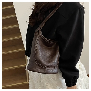 Detail of a dark brown lychee leather bucket bag with an adjustable shoulder strap