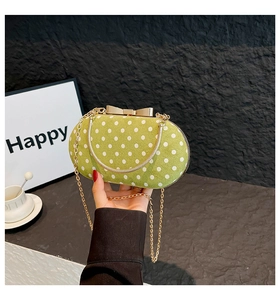 Detail of green polka dot evening bag with gold bow clasp and metal handle