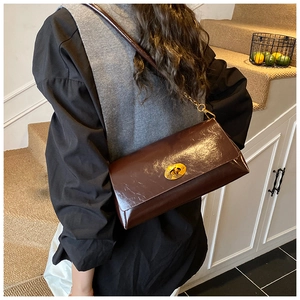 Détail du sac bandoulière vintage avec fermoir ovale doré sur rabat en cuir marron foncé