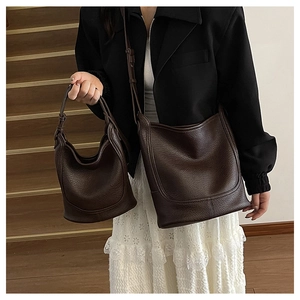 Detail of dark brown pebble leather shoulder and handbag set on wood background