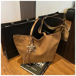 Detailed macro of dark brown suede tote bag featuring FREE COLOR logo and star pendant