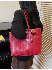 Red tote bag with wave texture and festive ribbon shown on model back view