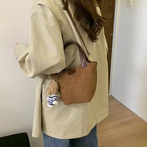Brown suede tote bag shown on model wearing light trench coat for daily casual style