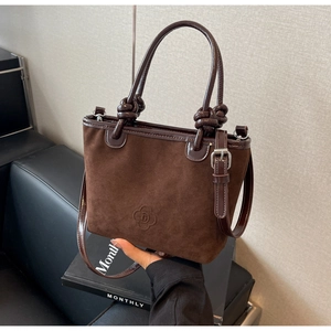 Detail of dark brown suede bucket bag with patent leather trim and embossed floral logo