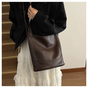 Detailed texture of dark brown lychee leather bucket bag with adjustable shoulder strap