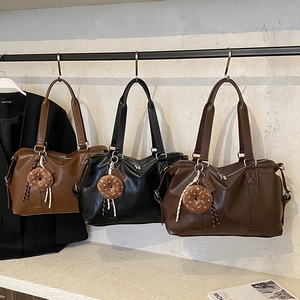 Detail of faux leather tote bags in tan, black, and coffee with cute donut plush charms
