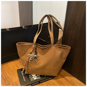 Detailed close-up of brown suede tote bag with leopard star charm and embossed logo