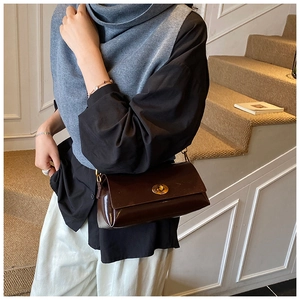 Détail d'un sac sous les bras en cuir ciré marron foncé avec une boucle dorée