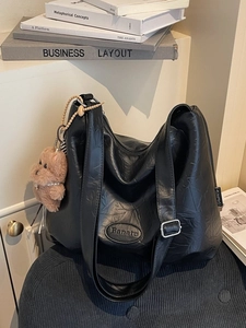 Retro black faux leather bucket bag with pleated texture and plush puppy pendant charm