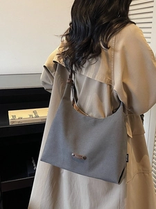 Grey canvas underarm tote bag with leather strap, shown on model for daily commuting