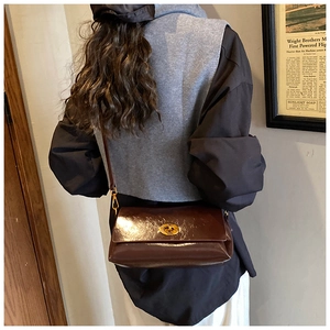 Gros plan d'un sac à bandoulière vintage en cuir marron brillant avec fermoir doré