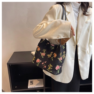 Detailed embroidery of colorful flowers on a black canvas tote bag for casual daily use