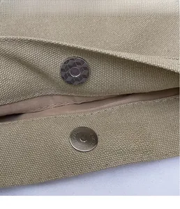 Dettaglio della chiusura magnetica in metallo con trama geometrica su borsa in tela