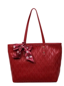 Quilted red tote bag with scarf detail and bronze rivets in a minimalist studio setting