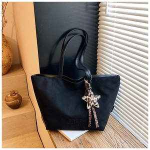 Detail view of black tote bag with Free Color print and leopard star charm accessory