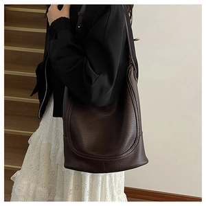 Deep brown lychee leather bucket bag styled with a minimalist outfit in a daily setting