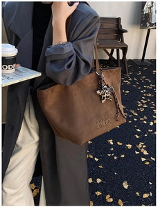 Brown suede tote bag with leopard star charm and embossed logo in a street style view