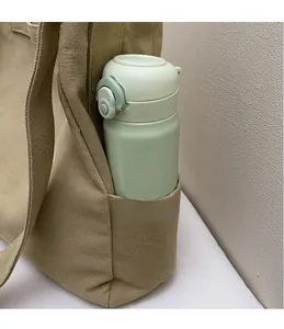 Dettaglio di una borsa tote in tela beige con tasca laterale e borraccia per l'acqua