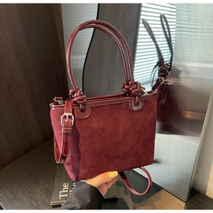 Close-up of burgundy suede bucket bag with floral embossing and patent leather handle