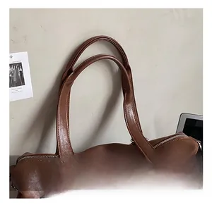 Detail of dark brown leather handles and premium metal zipper on travel bag